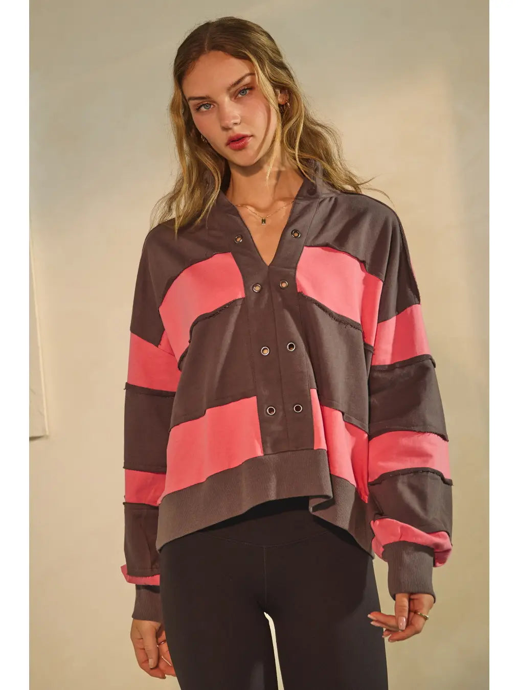 Washed color block pullover with grommet placket and raw-edge seams.